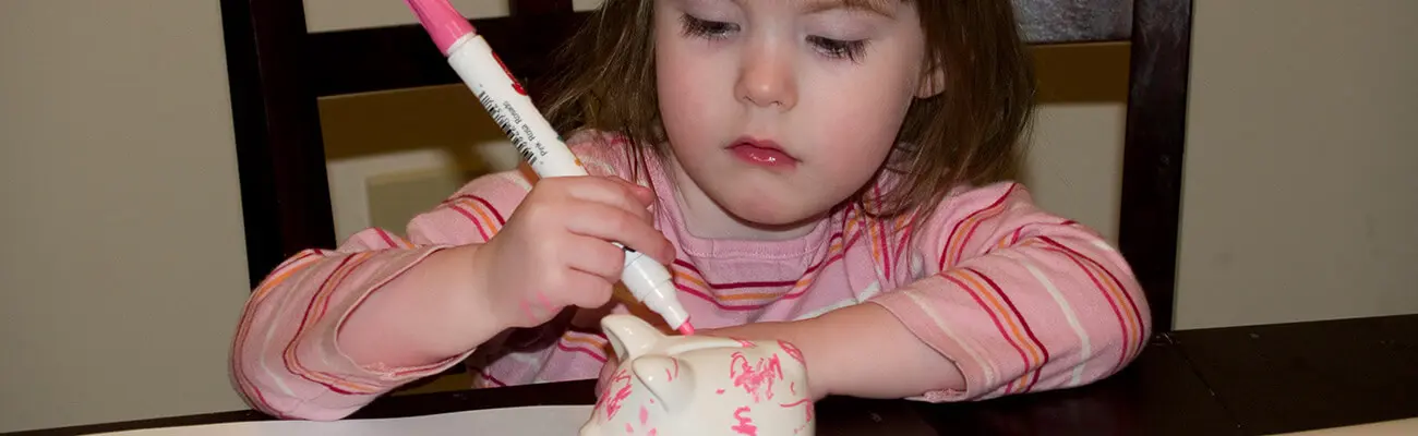 girl drawing on her piggy bank