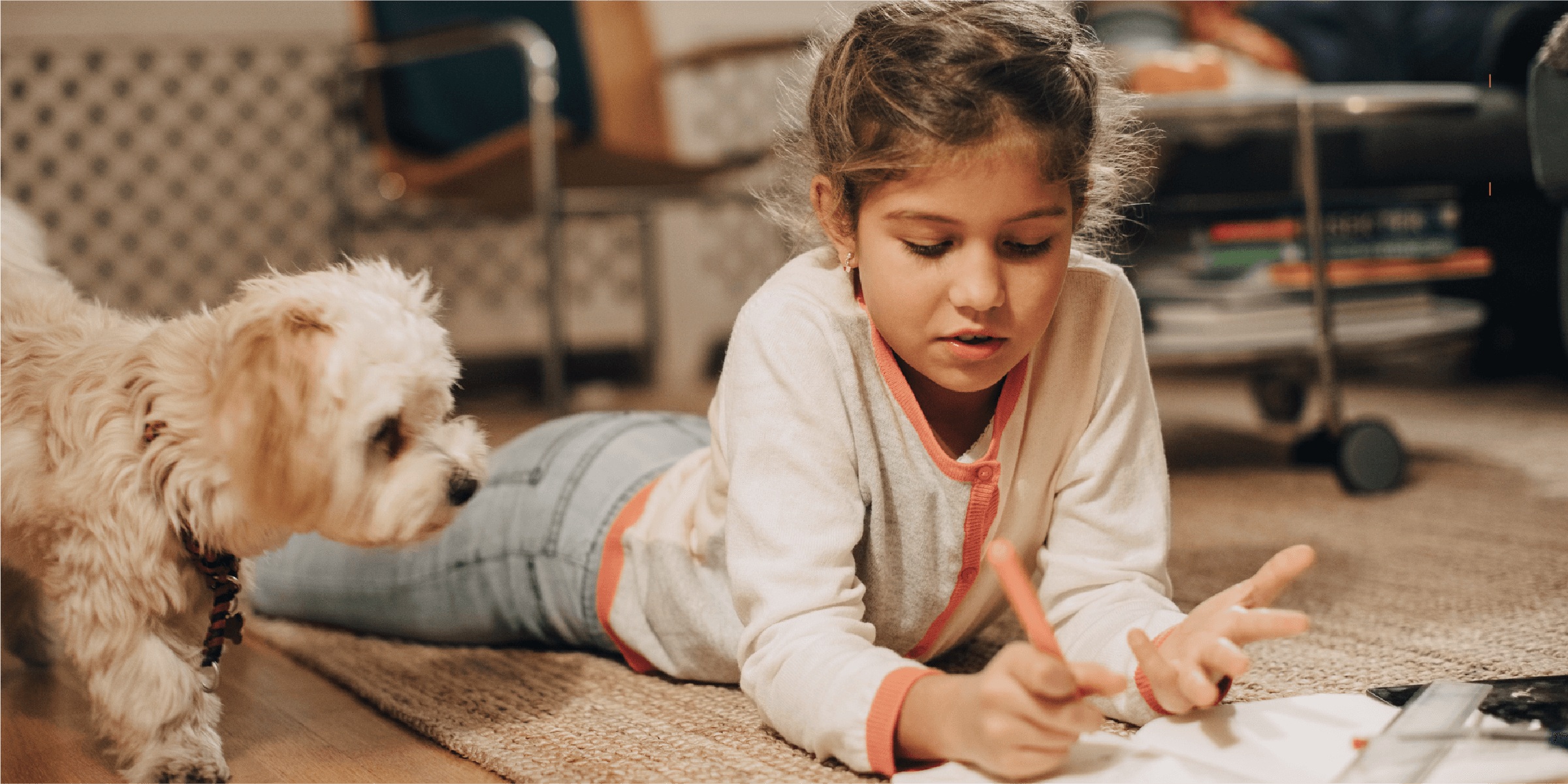 girl writing in a notebook next to a dog