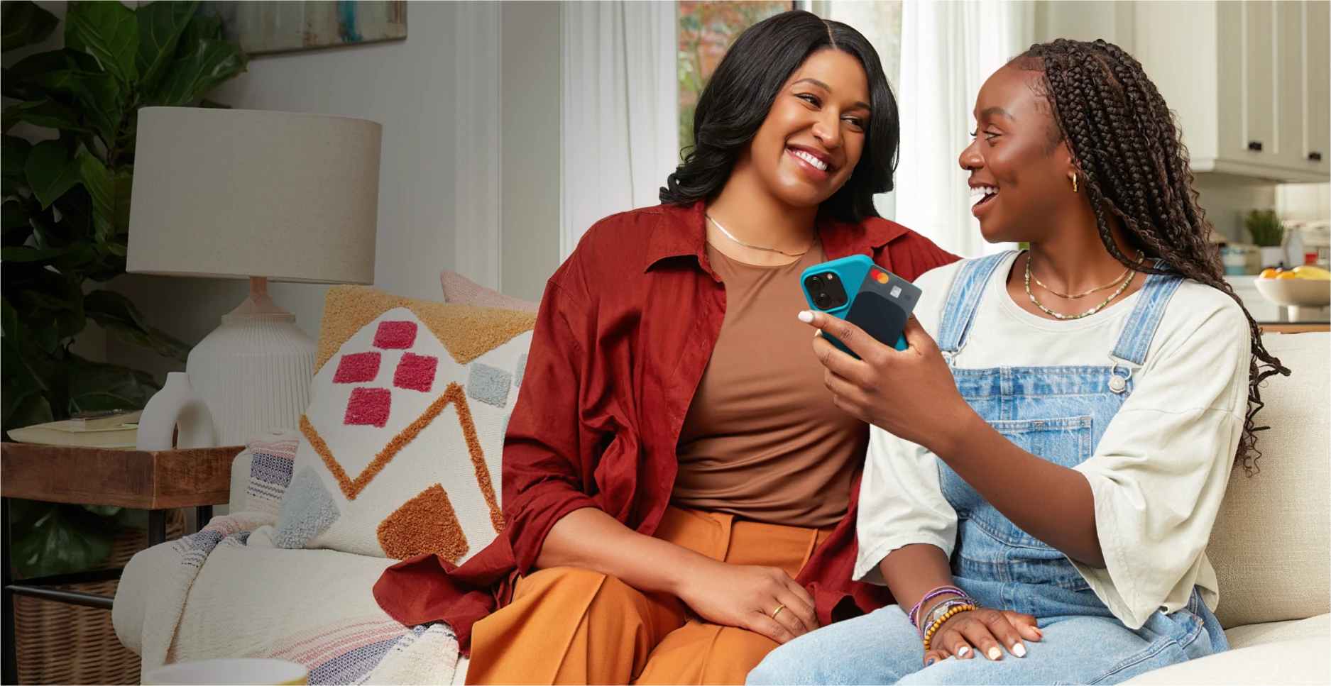 Mother and daughter on a couch holding a card and cellphone