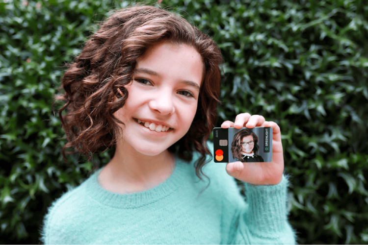 young girl holding her greenlight debit card