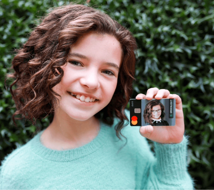 young girl holding her greenlight debit card