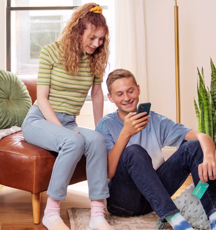 two teenagers looking at the teen boys smart phone
