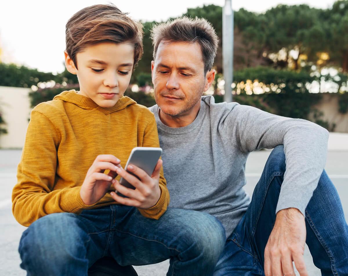 son holding smartphone next to his father