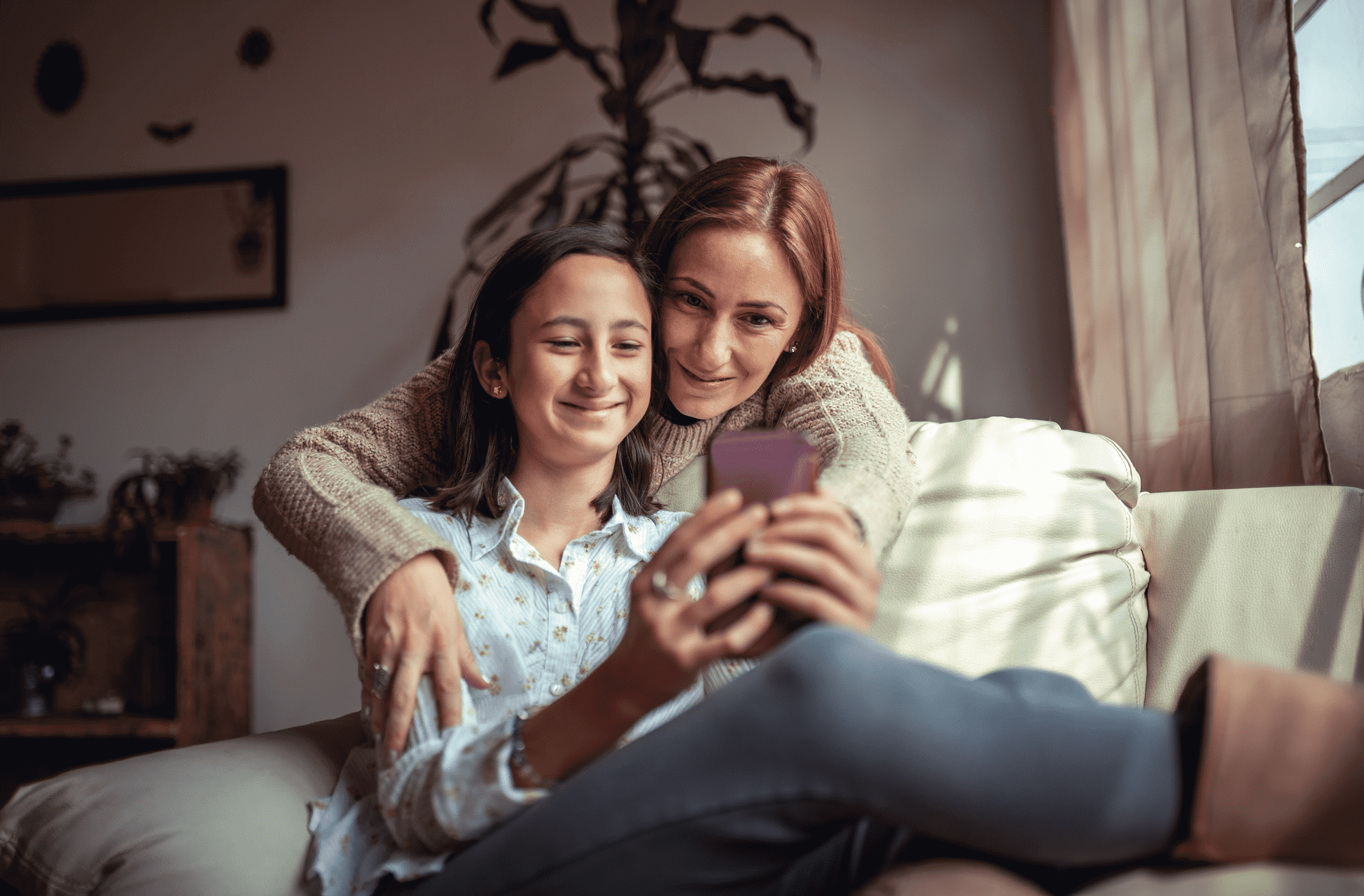 Mom and teen daughter using Greenlight’s investing app on a mobile phone to research stocks