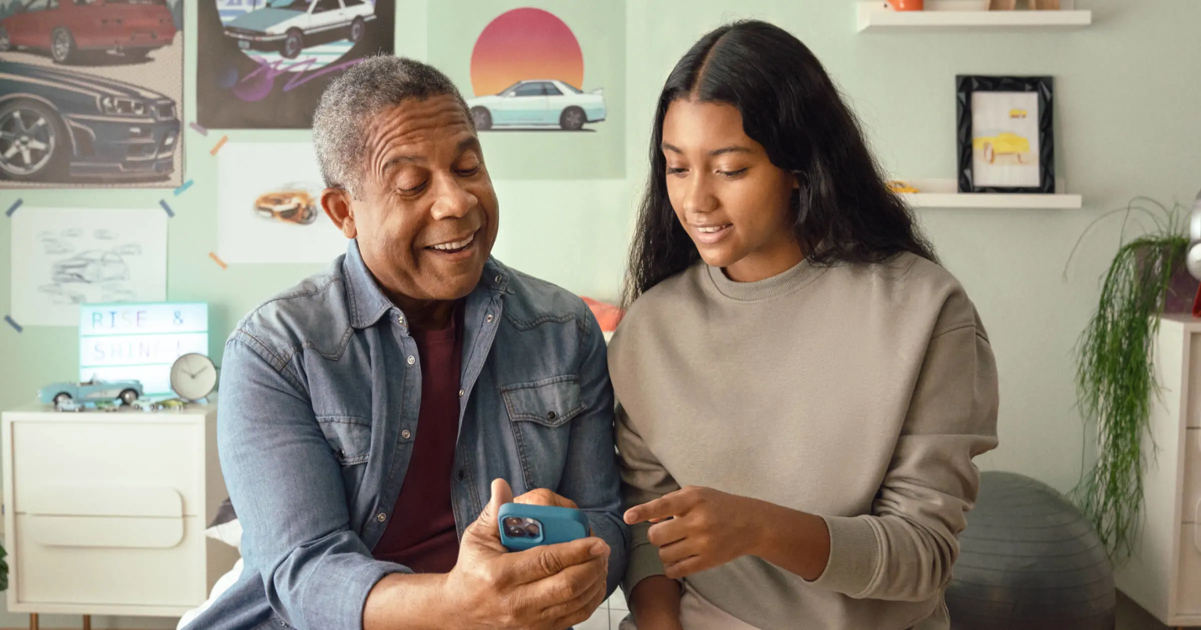 Father and daughter sitting and looking at Greenlight's parent credit card app with cash back