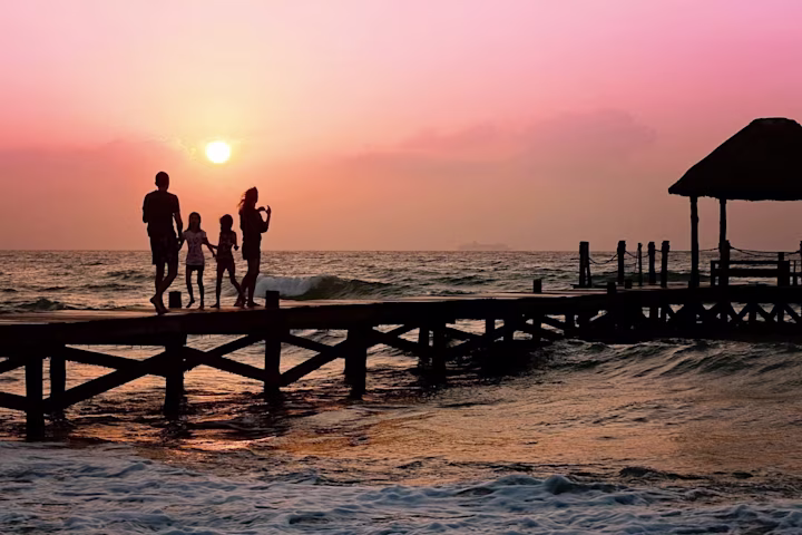 Family standing on a dock during sunset.