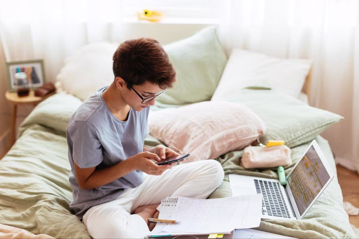 Person using a phone while sitting on a bed