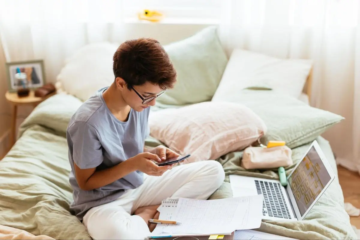 Person using a phone while sitting on a bed