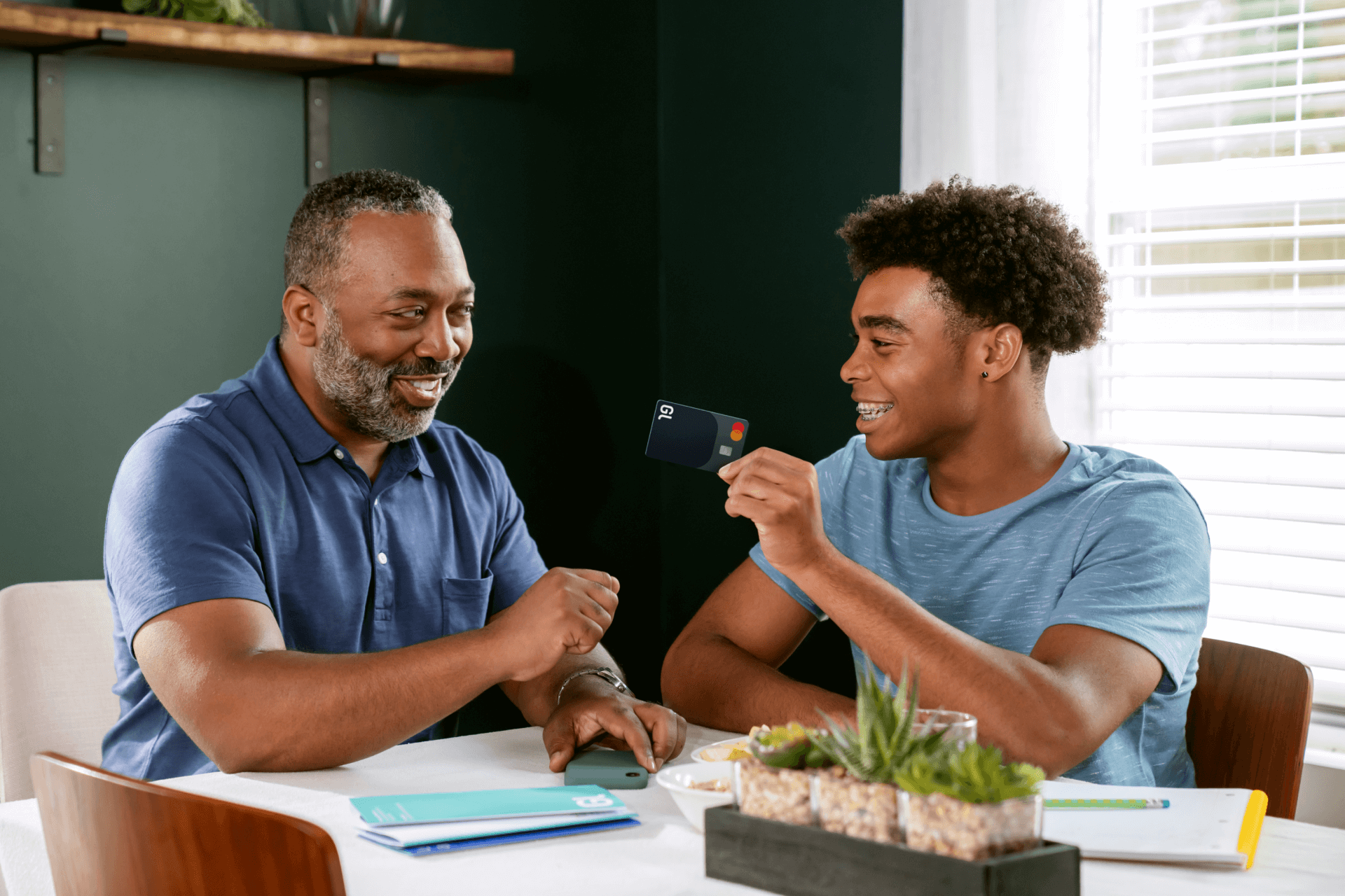 Father and Son Discussing Finances with Debit Card