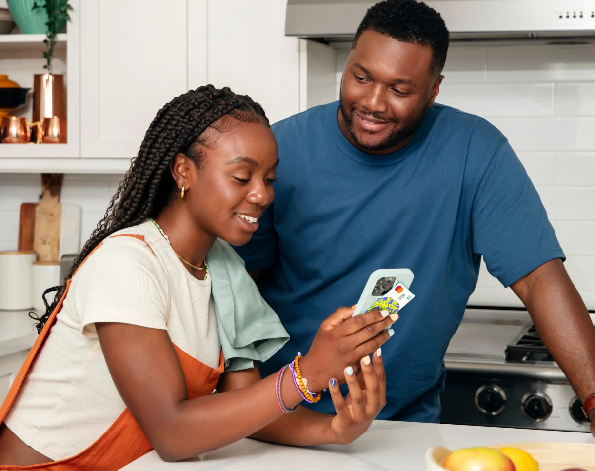 Father and daughter holding a cellphone and a custom card in a kitchen