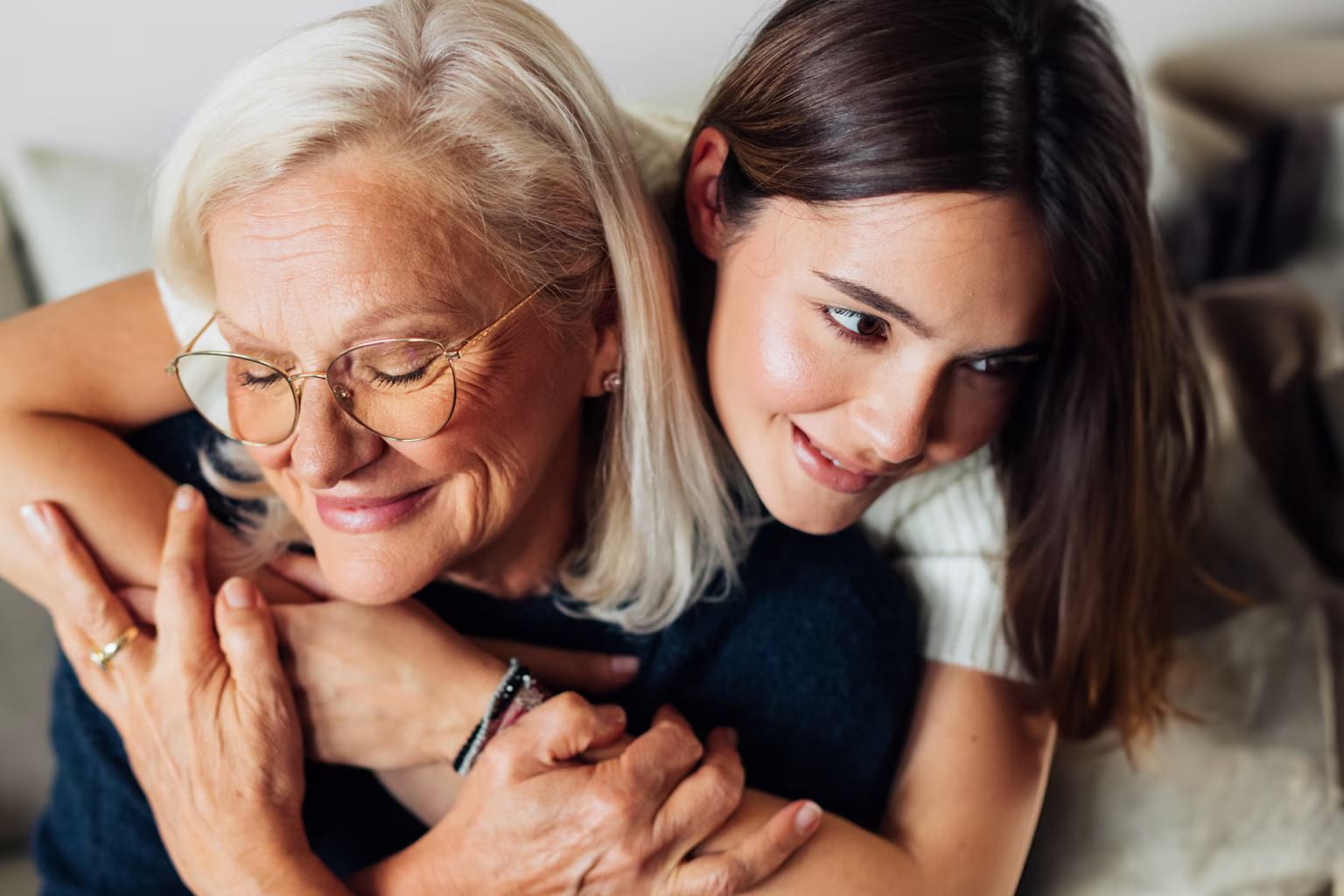 Young woman smiling putting her arms around her elderly mother.
