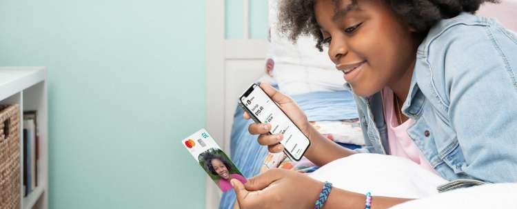 teen girl looking at her greenlight custom debit card and app