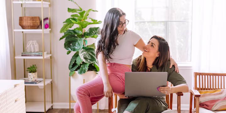 Mom and daughter chatting in living room about safety when using internet devices