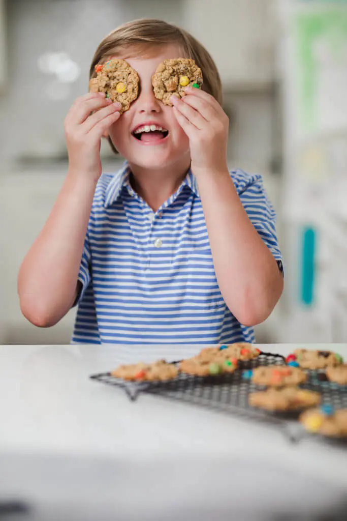 young boy smiling and holding cookies over his eyes