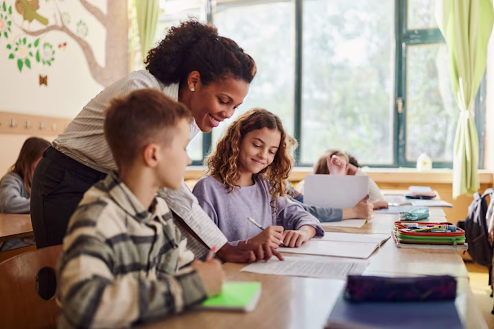Teacher showing two young students an assignment.
