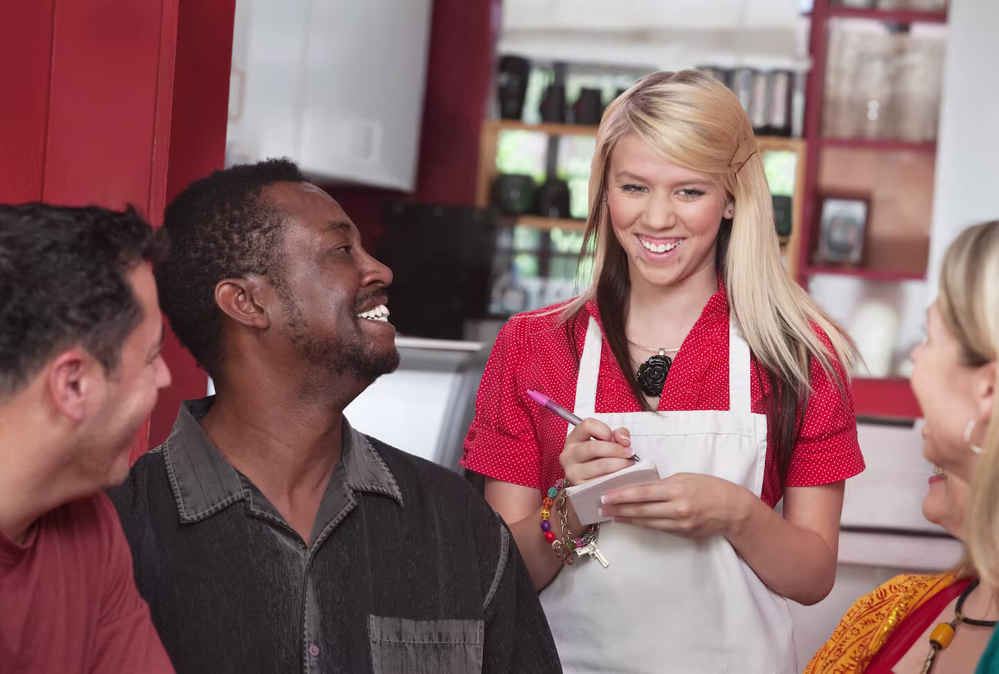 How does direct deposit work: A young waitress writes down the orders for a smiling table of customers