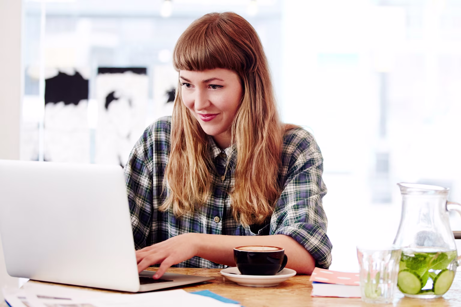 Young adult woman doing taxes on her laptop in a coffee shop, reading blog: What are taxes?