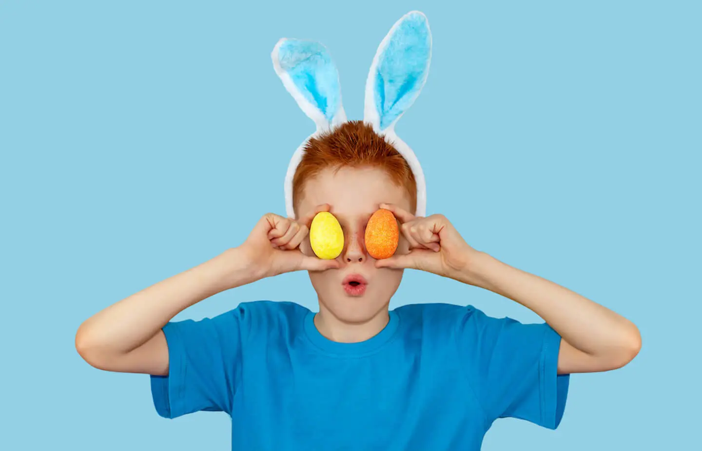 Spring activities for kids: boy covering his eyes with 2 eggs
