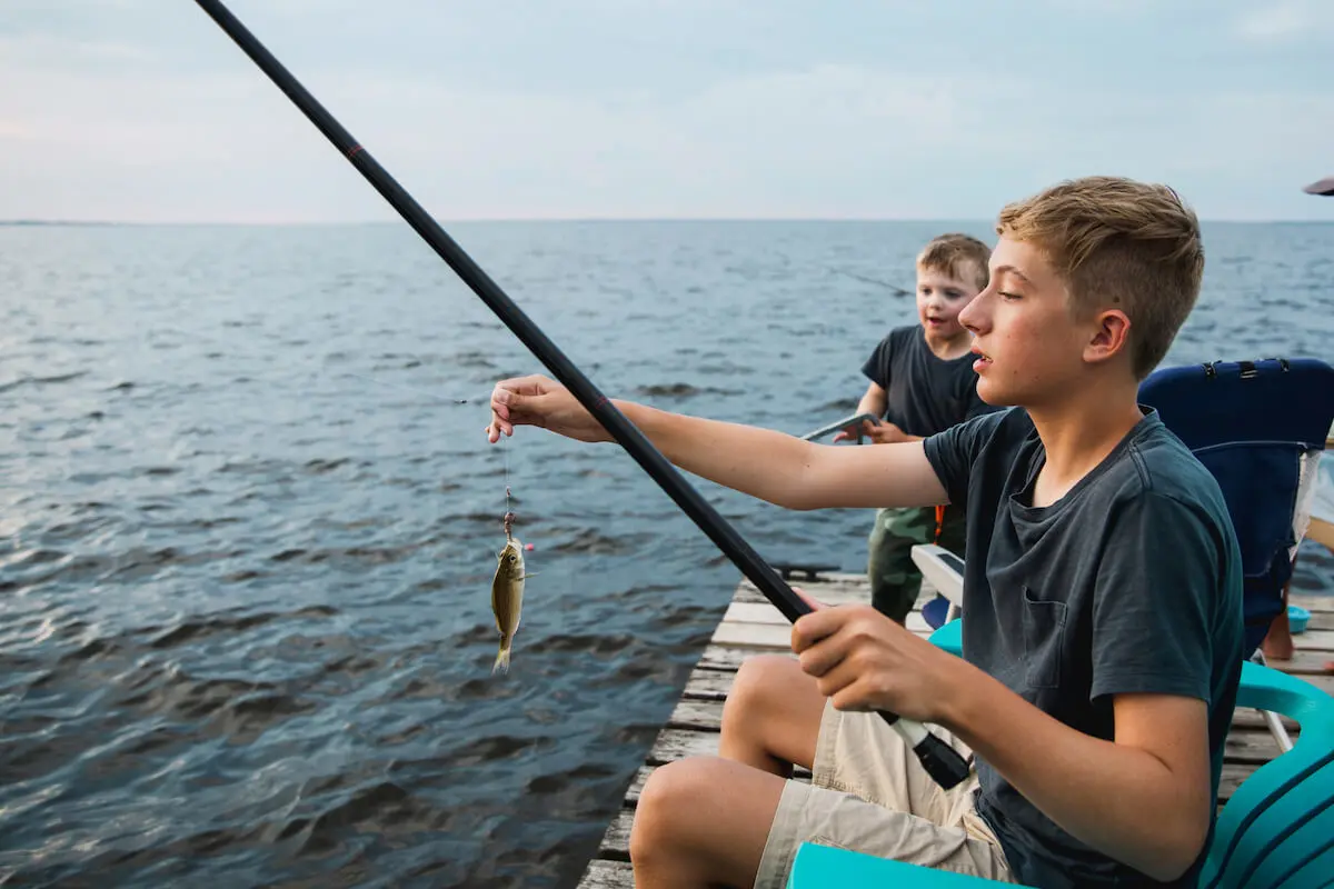 Boy holding a fishing rod and a hooked fish