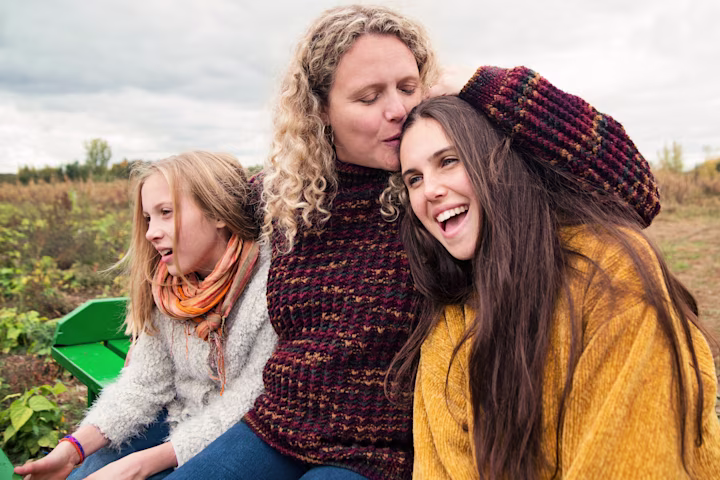 Mom and two daughters outside together.