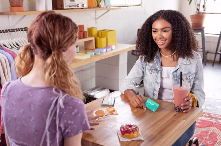 Two teen girls having boba and donuts while discussing finances with Greenlight's money app for teens