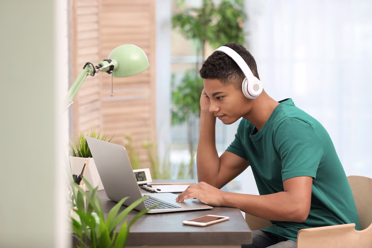 Teenager wearing headphones and using a laptop