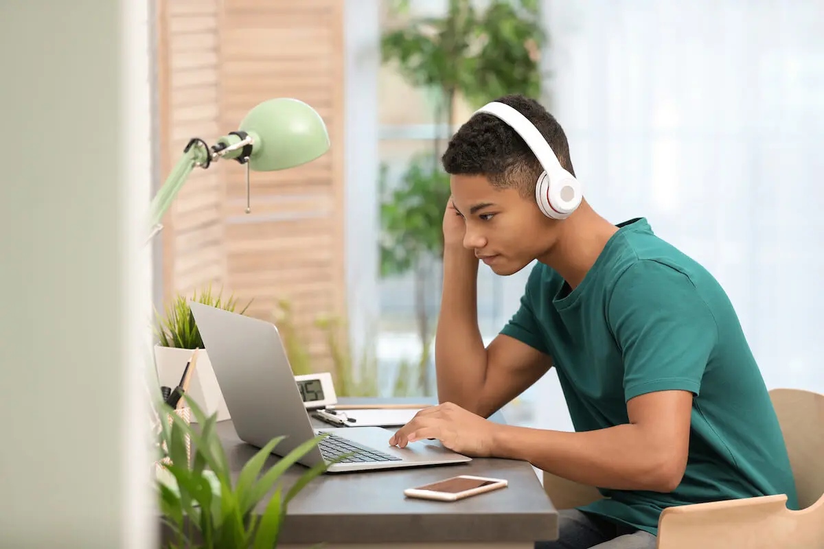 Teenager wearing headphones and using a laptop