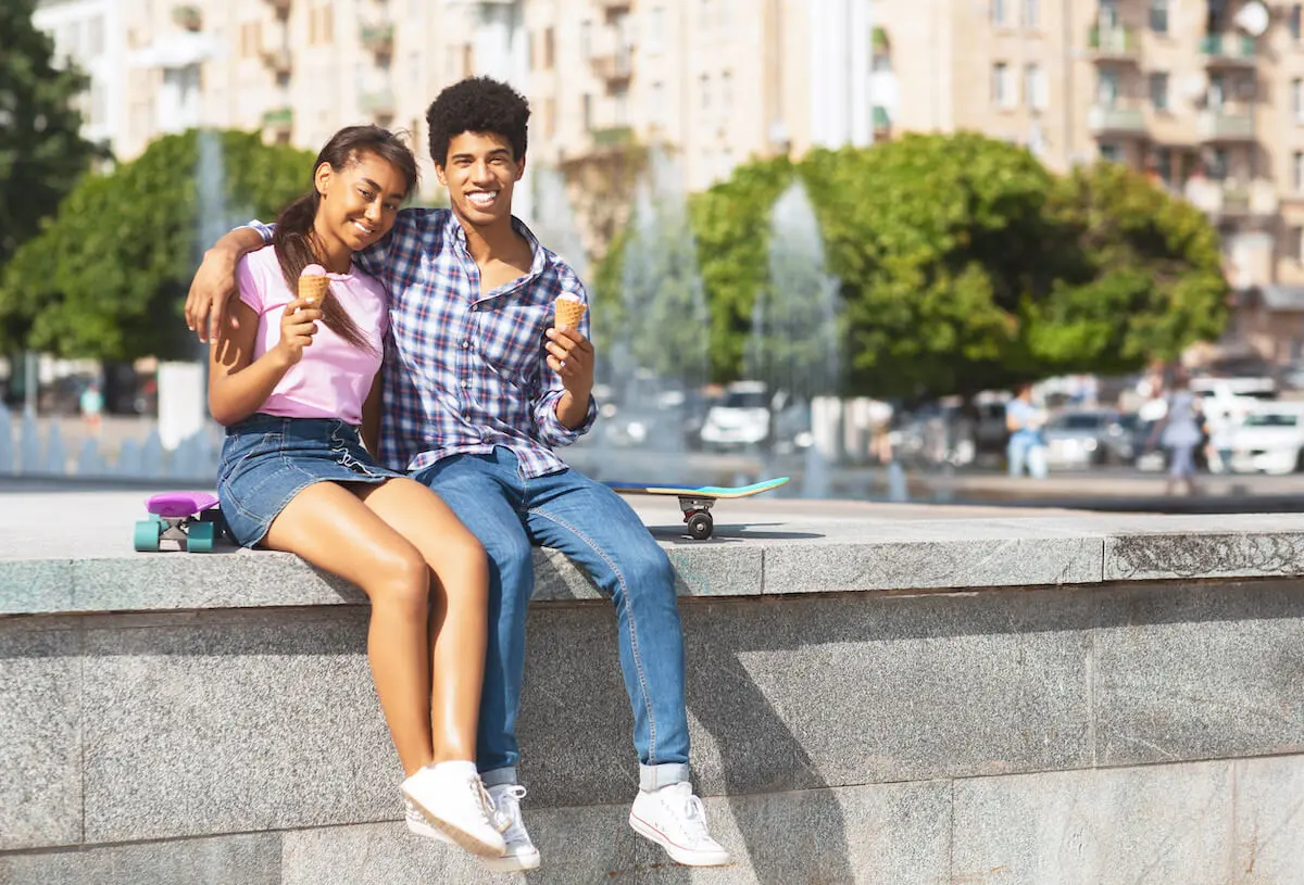 Date ideas for teenagers: Two teens sit on the edge of a fountain and eat ice cream