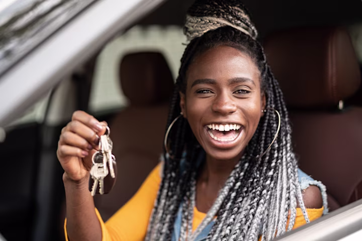 Young teen girl holding keys excited about her first car: A guide for first-time car buyers.