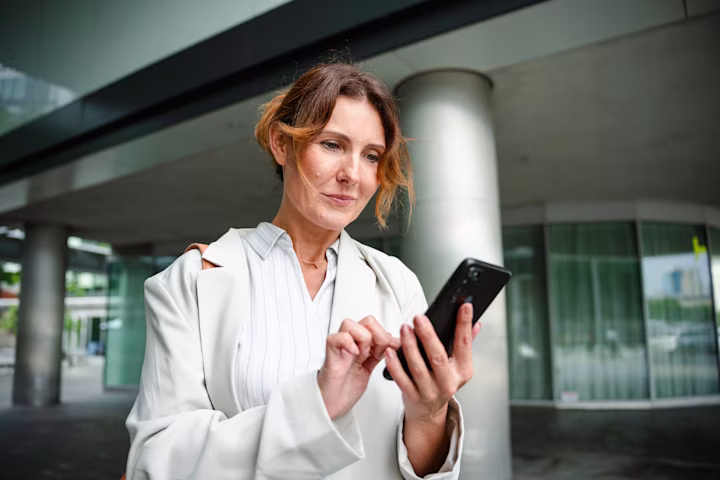 Woman looking at her phone while standing outside of a building.