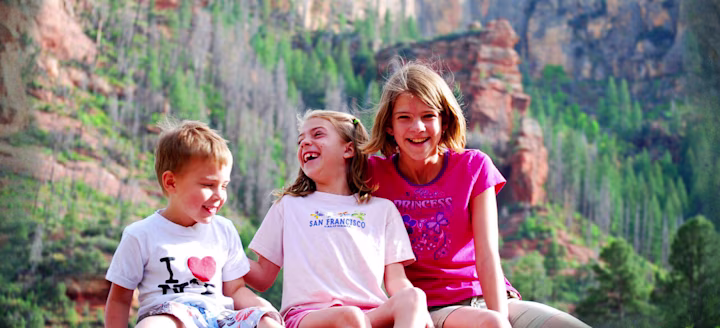 three kids laughing outside in a park