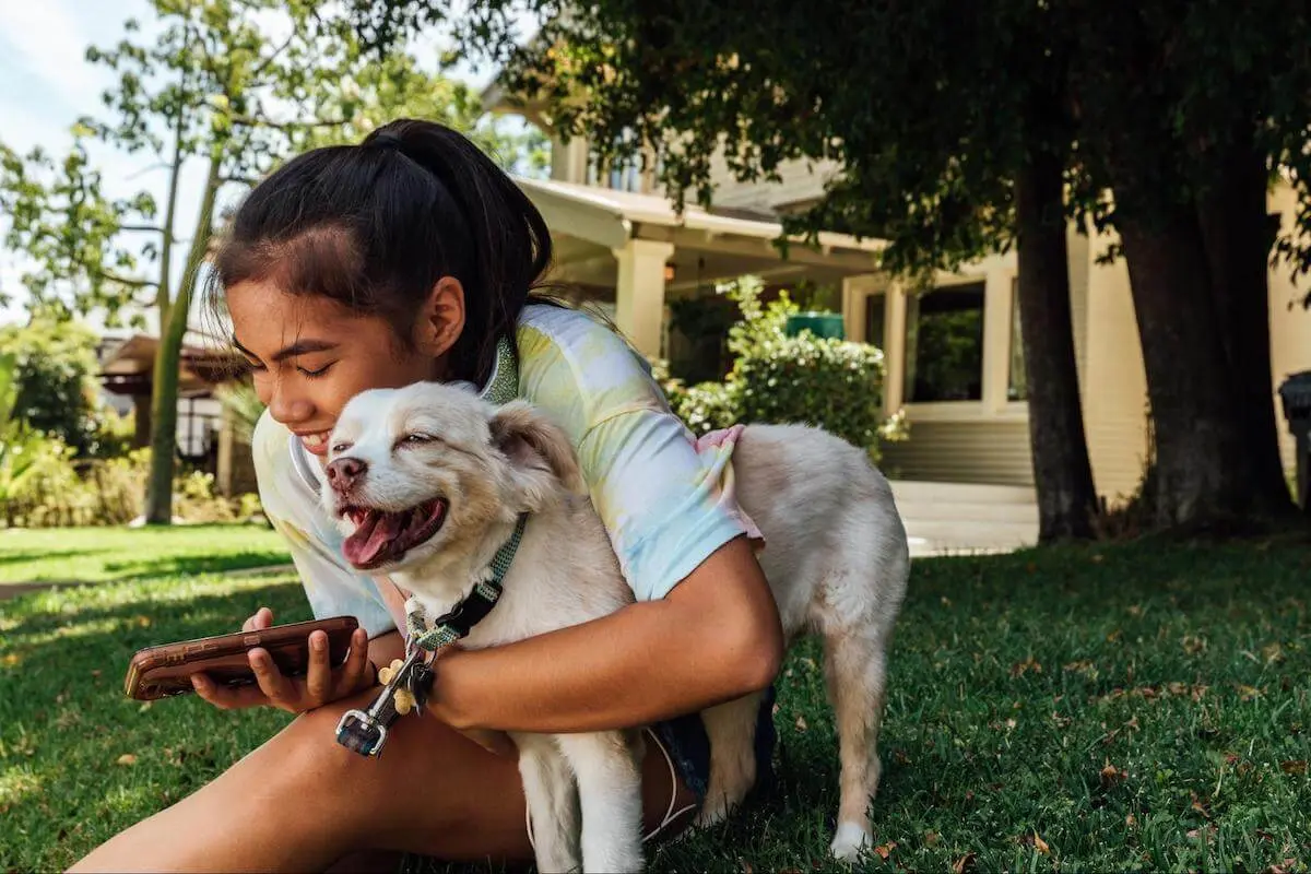 Jobs for 10 year olds: girl using her phone while hugging a dog