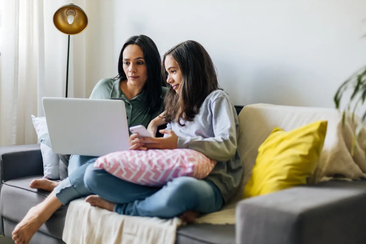 How does direct deposit work: A mother and daughter sit on their couch and use a laptop together