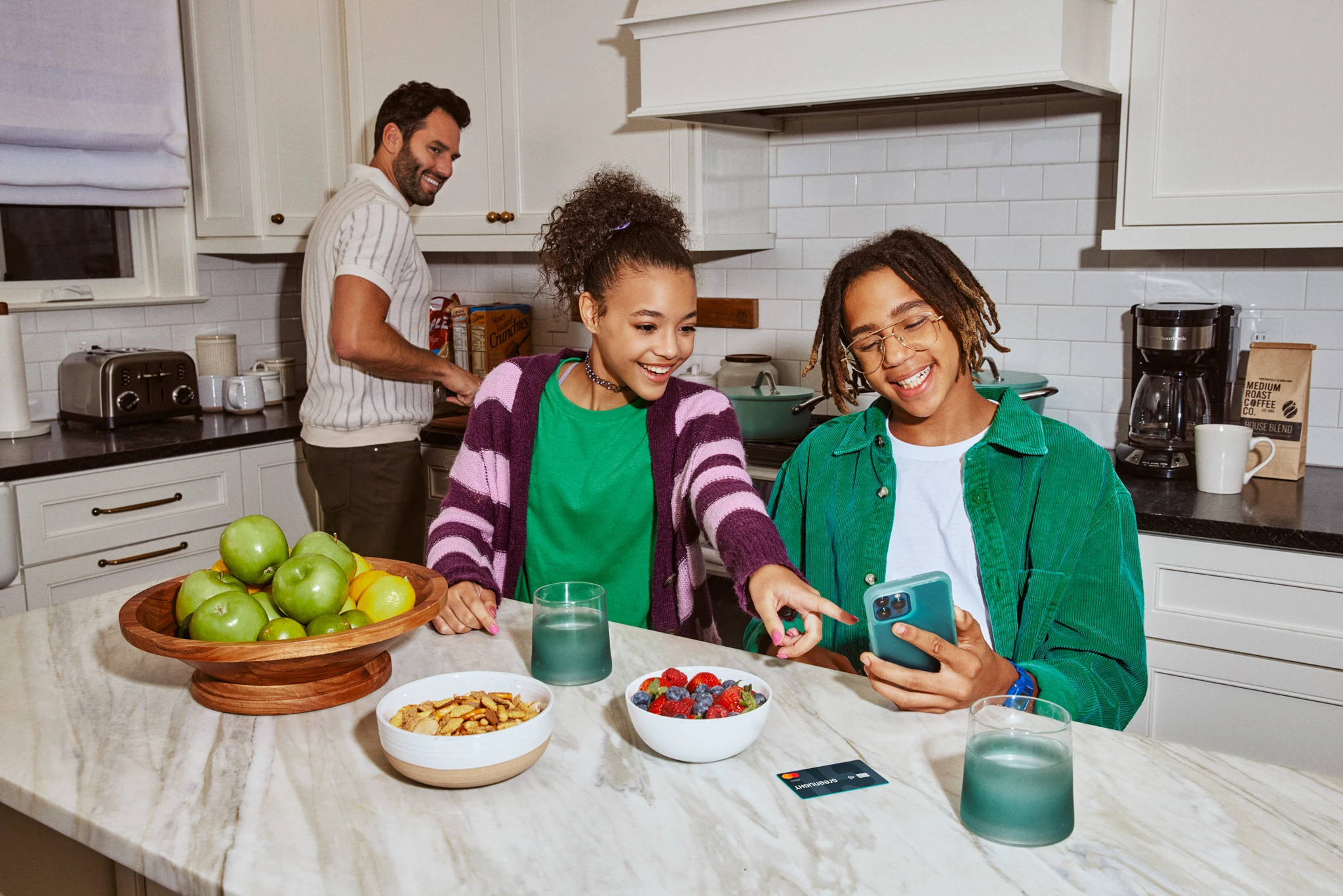 Family in kitchen looking at phone