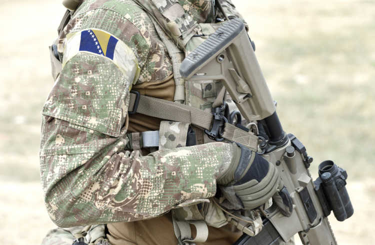 Soldier with assault rifle and flag of Bosnia and Herzegovina on military uniform