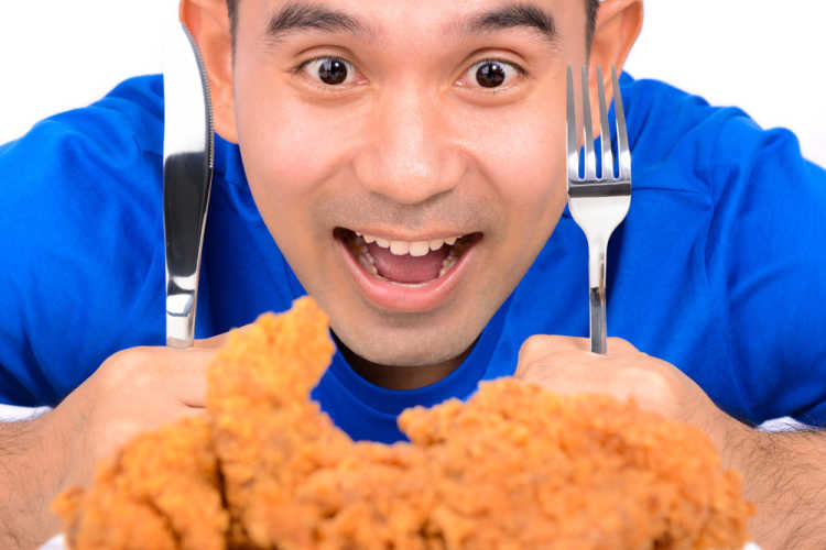 man eating fried chicken with knife and fork