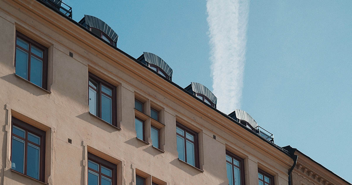Beige, äldre lägenhetshus i Stockholm, Sverige med blå himmel i bakgrunden.