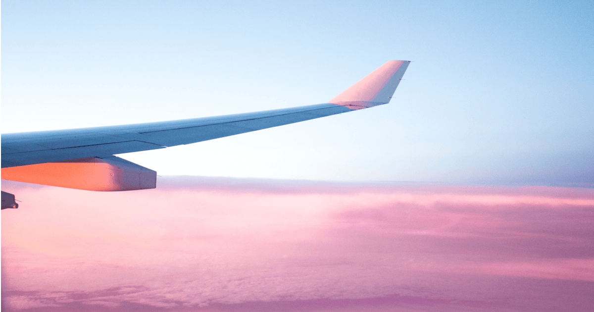 Flygplansvinge mot en rosa himmel.