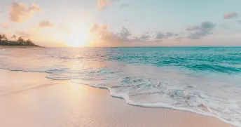 Strand med turkosa vatten i solnedgången. 