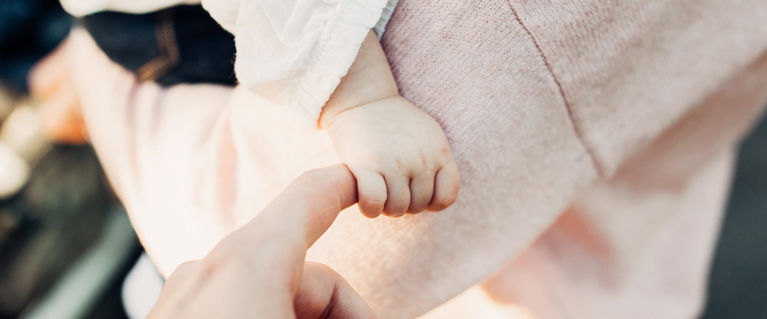 Bebis håller i förälders finger