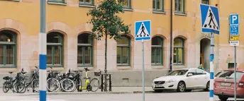 Vit och röd bil parkerade i olika riktningar på en gata med ett orange lägenhetshus i bakgrunden