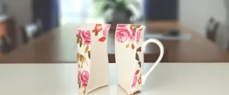 Trasig, blommig kaffekopp på en vit bänk.