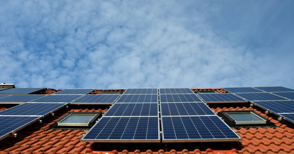 Solceller på tegelhustak med blå himmel i bakgrunden