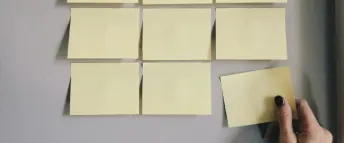 En kvinna sätter upp post-it-lappar på en vit bakgrund