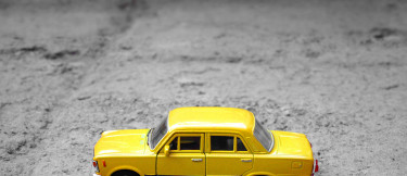 gul leksaksbil med grå bakgrund