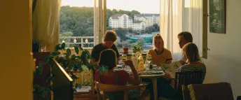 En grupp vänner äter sitter runt ett bord och äter middag ihop.
