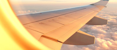 Utsikten från ett flygplansfönster med vit flygplansvinge och moln i bakgrunden