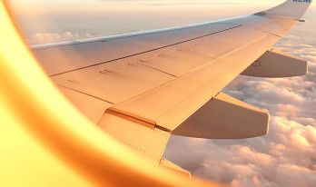 Utsikten från ett flygplansfönster med vit flygplansvinge och moln i bakgrunden