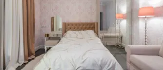 Säng i hotellrum med rosa detaljer. 