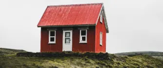 Litet rött hus stående på en gräskulle